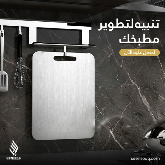 Metallic cutting board hanging on a marble wall with promotional text in Arabic.